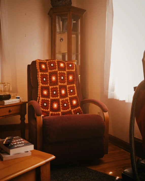 a chair in a corner with a crocheted blanket on it