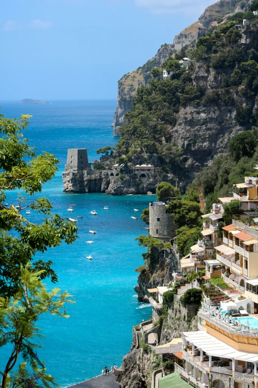 boats are moored in the blue sea near a mountain town