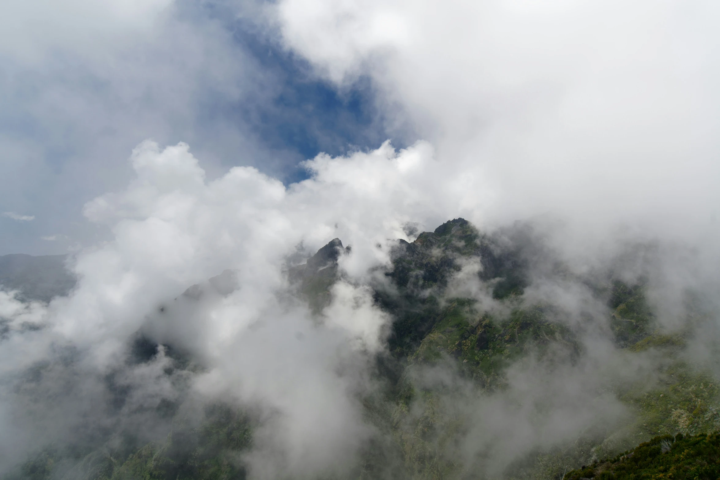 a mountain slope with clouds moving through it