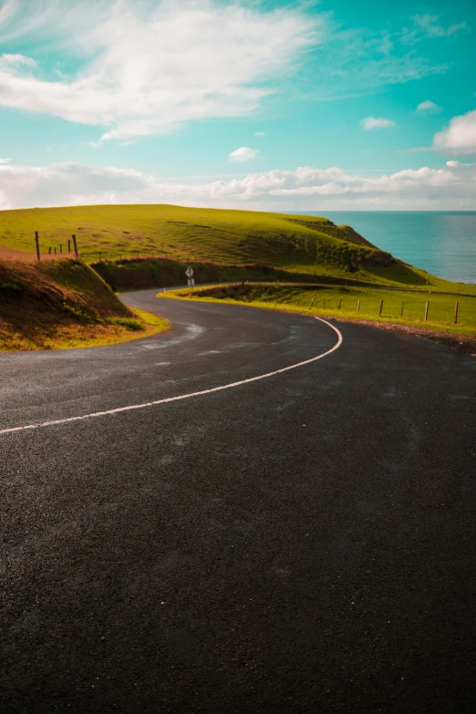 a winding road with hills and the ocean