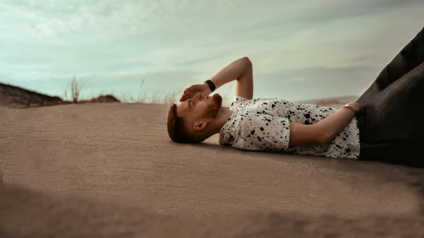 a male is lying in the sand and is making a funny face