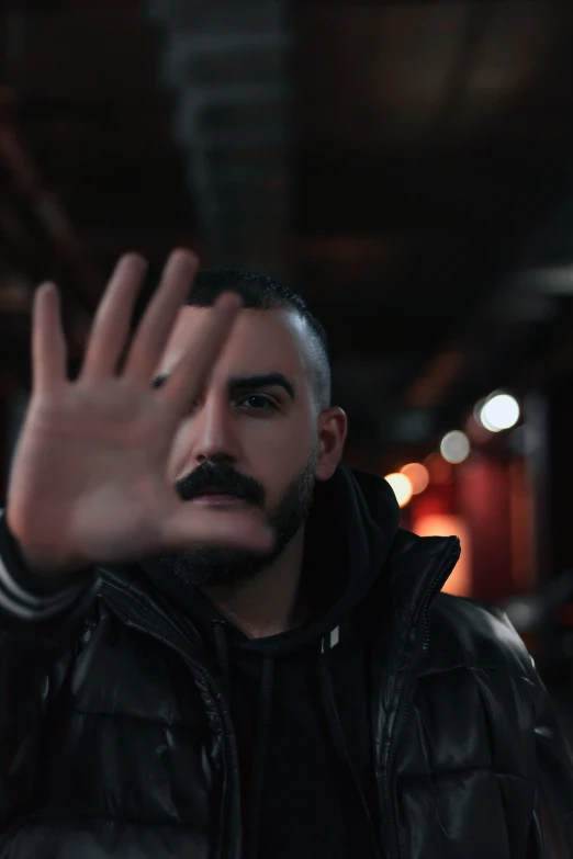 man in leather jacket posing with his hands in the air