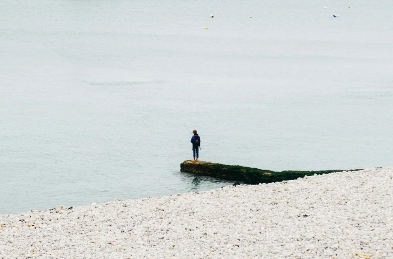 a person standing in shallow water next to the shore