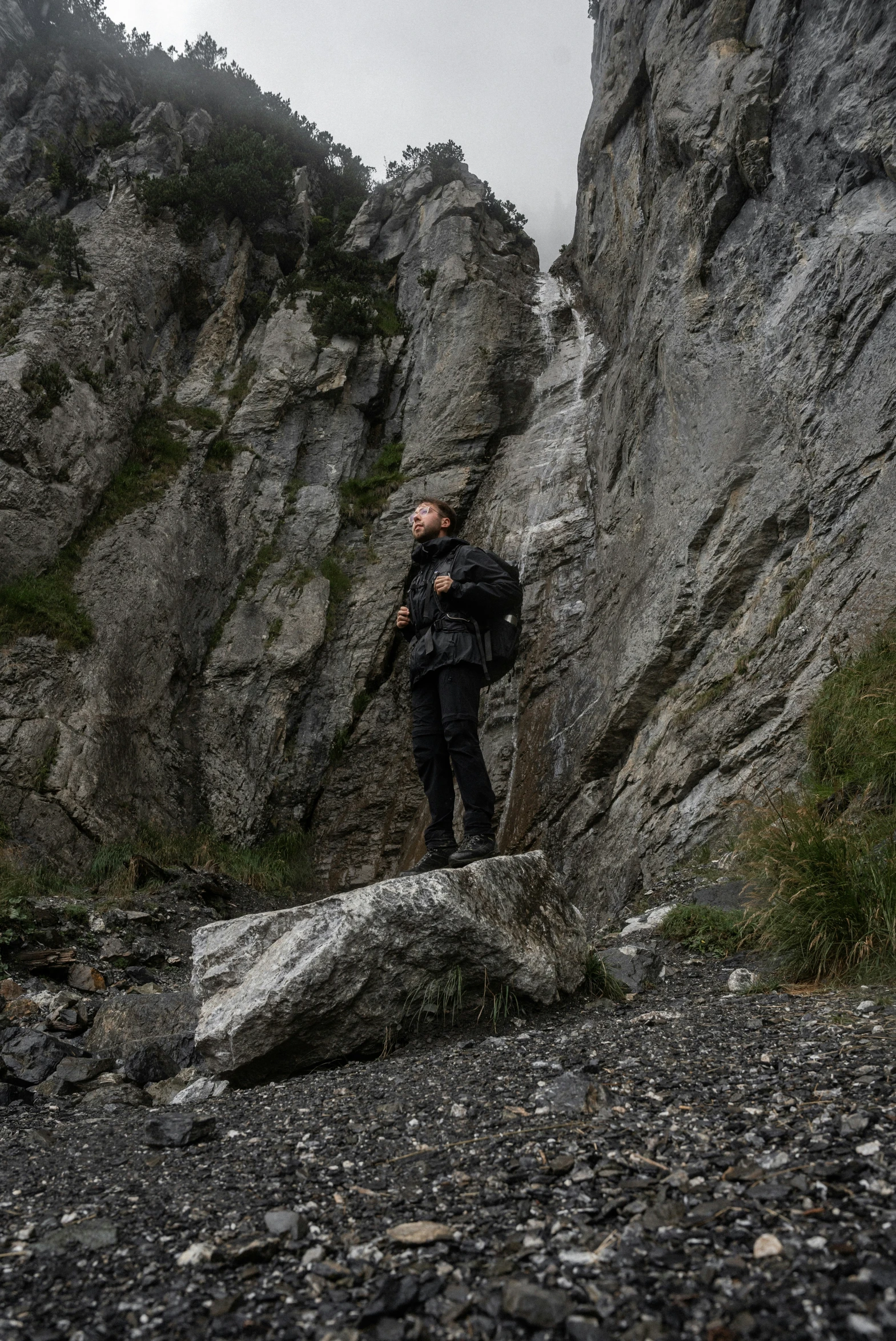 a man standing on a rock on the side of a mountain