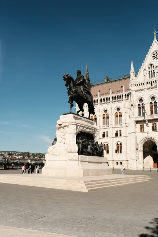 there is a horse statue in the foreground and people on the sidewalk