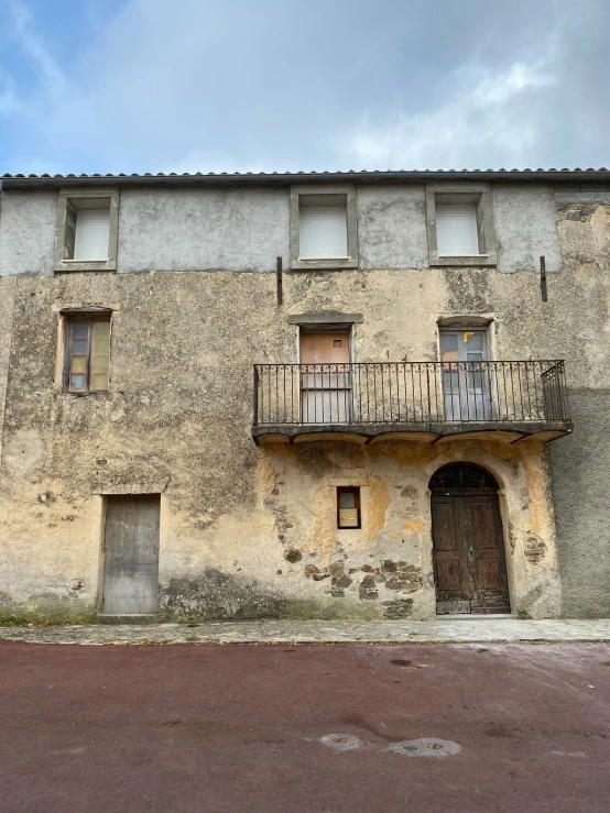 a old rundown building has a balcony and windows