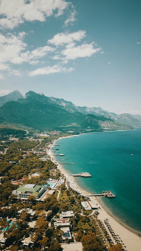 a scenic pograph of the ocean with buildings by the shore and the hills on the horizon