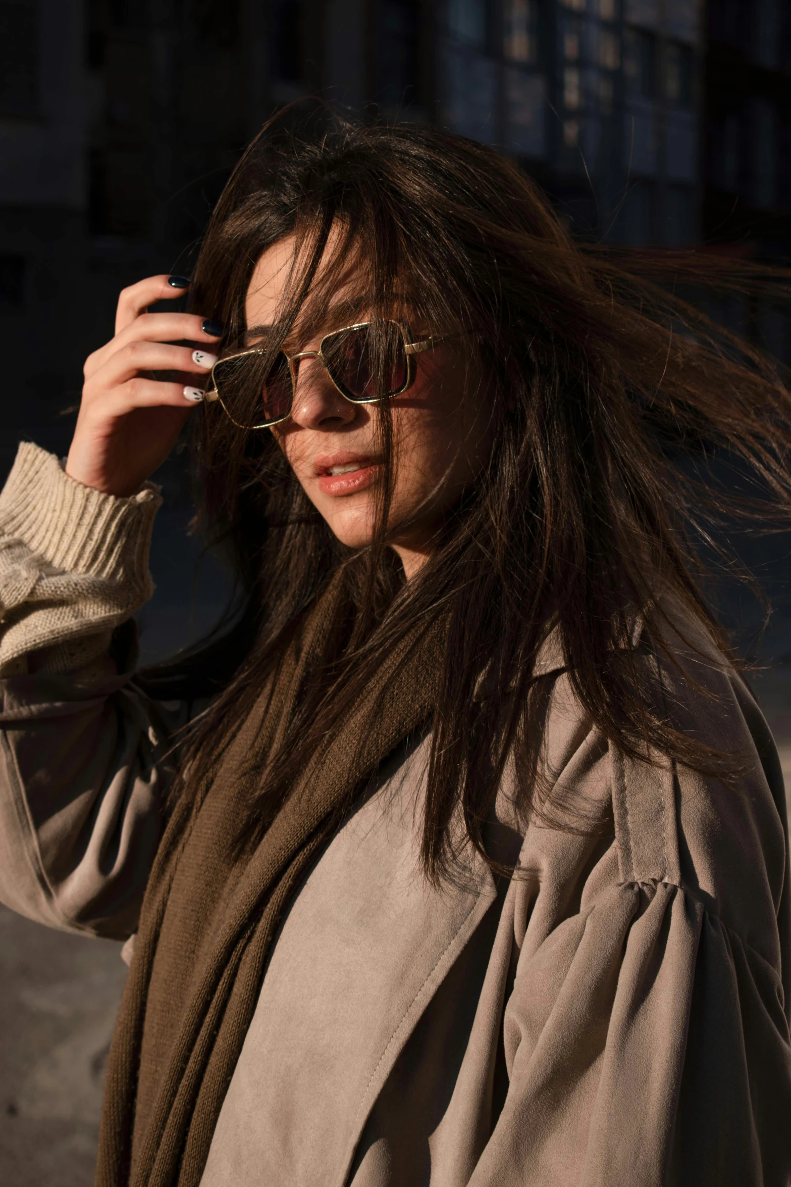 a woman in sunglasses with her hair blowing in the wind