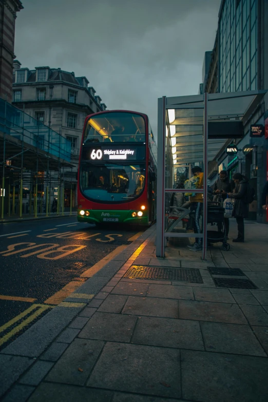 a red double decker bus driving past a building