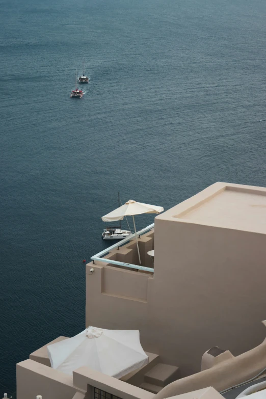 two tables with umbrellas on a cliff near water