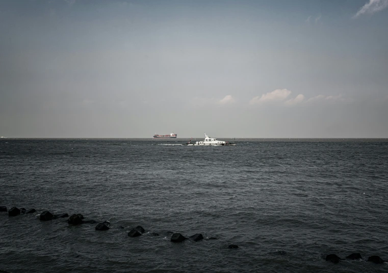 there are some boats in the ocean near a large boat