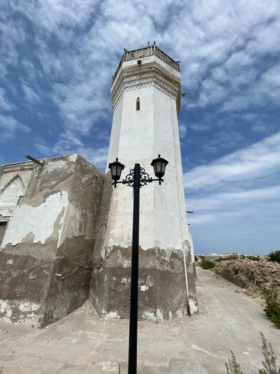 a white light tower in front of a cloudy blue sky