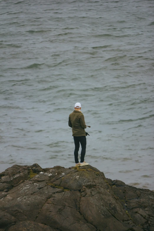 a man standing on a rocky shoreline in front of the water