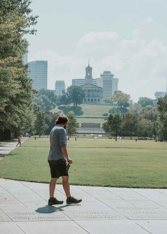 a person walking through a park looking at the grass