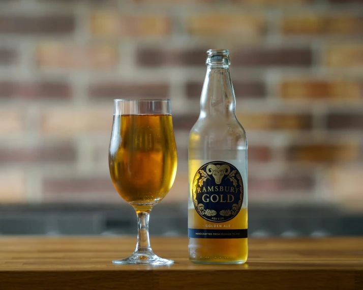 a beer in the foreground with a glass next to it on a wooden table