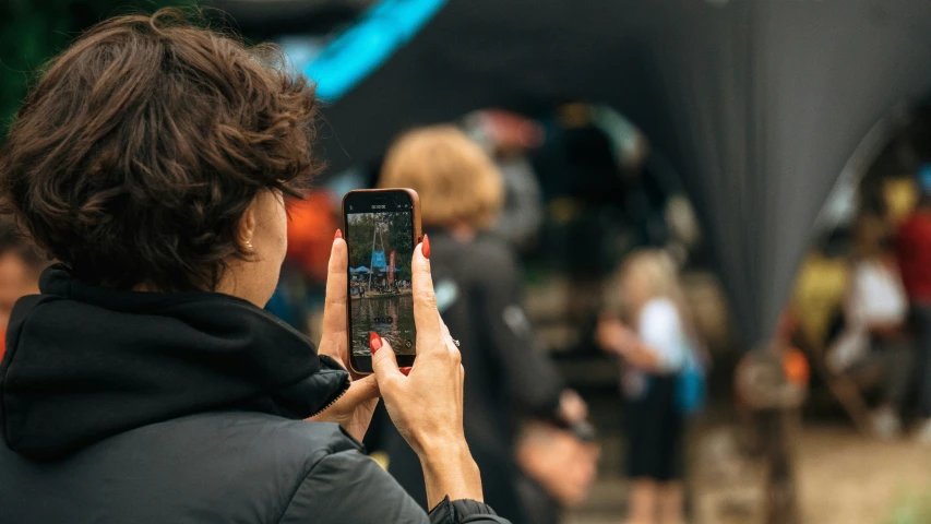 a woman in a black jacket taking a picture with her cell phone