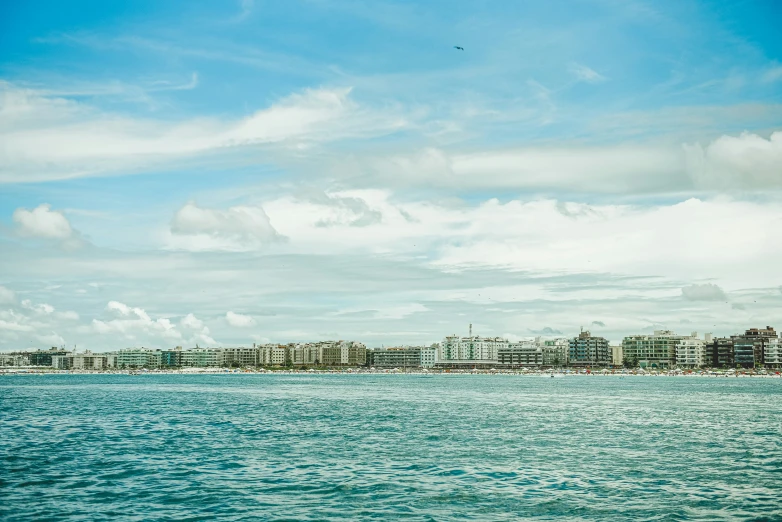 some tall buildings by the blue water under a cloudy sky