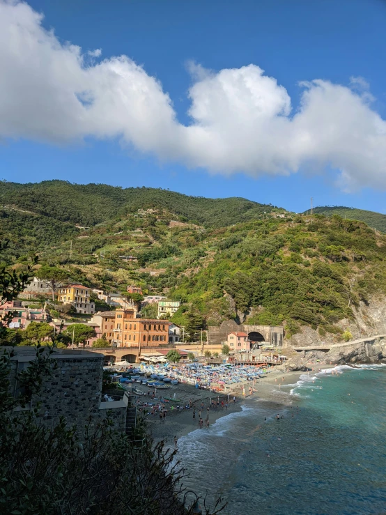 a large mountain side village on top of a hillside next to a sandy beach