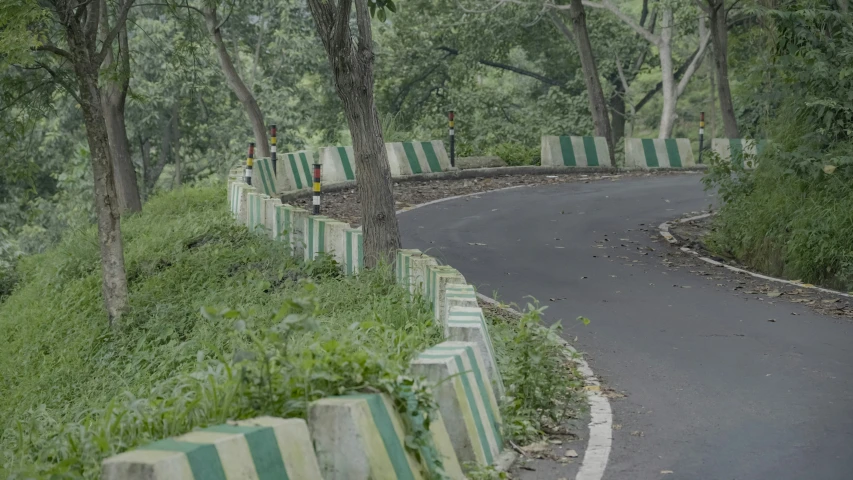 a curved road with a line of green and white striped benches on each side