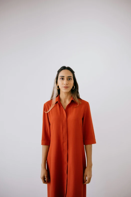 the woman stands wearing an orange shirt dress and black booties