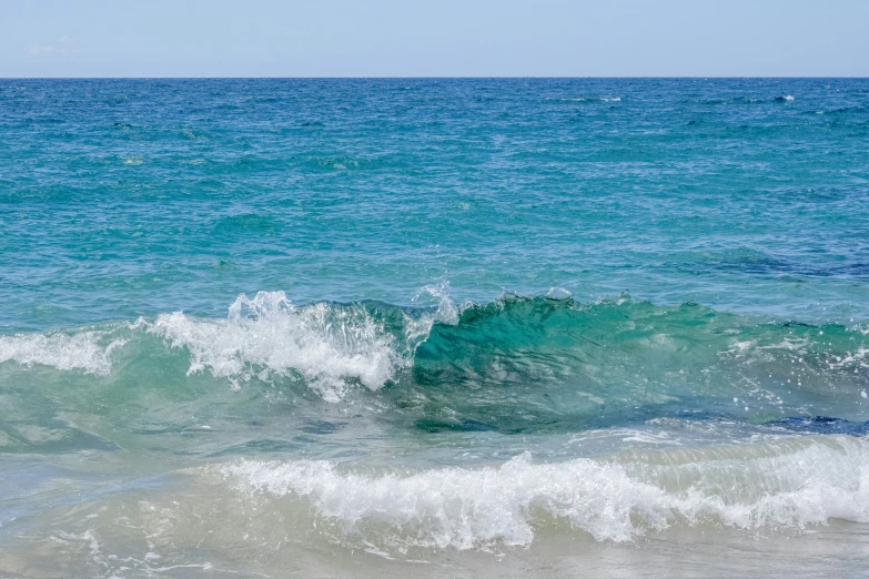 the ocean waves are getting crazy, and the blue sky is almost overcast