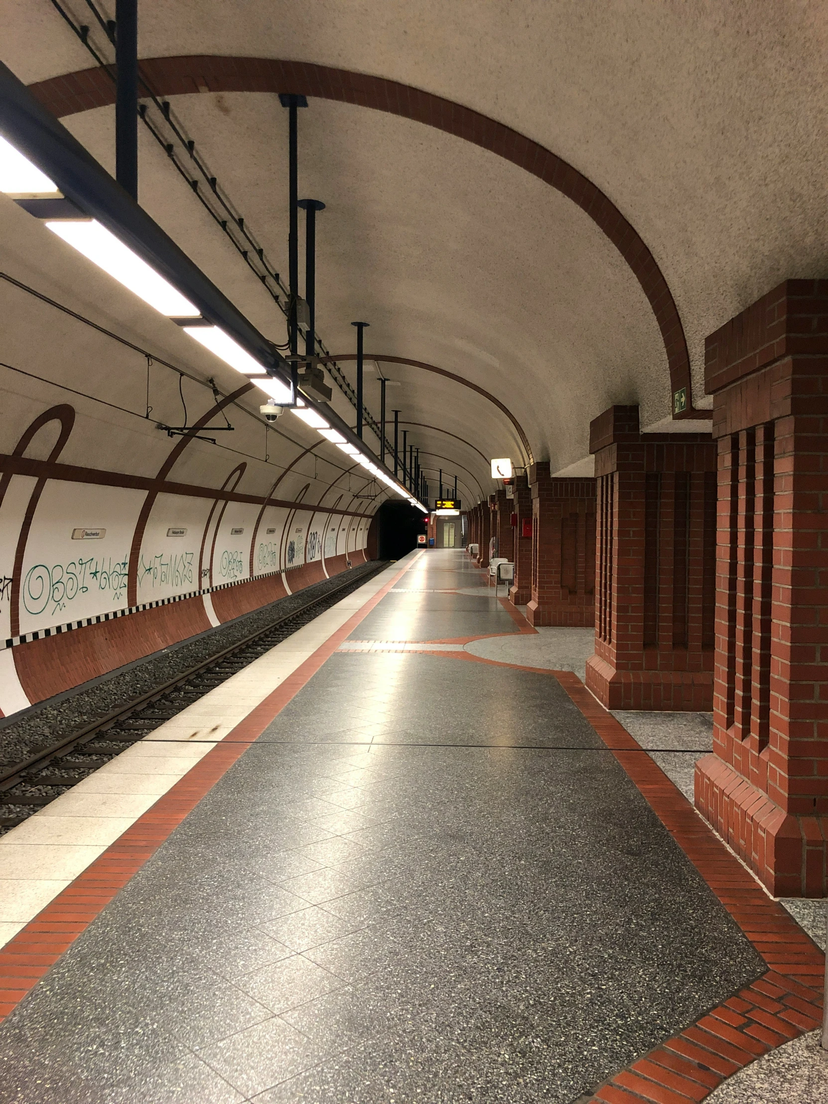 a long empty tunnel next to a red brick platform