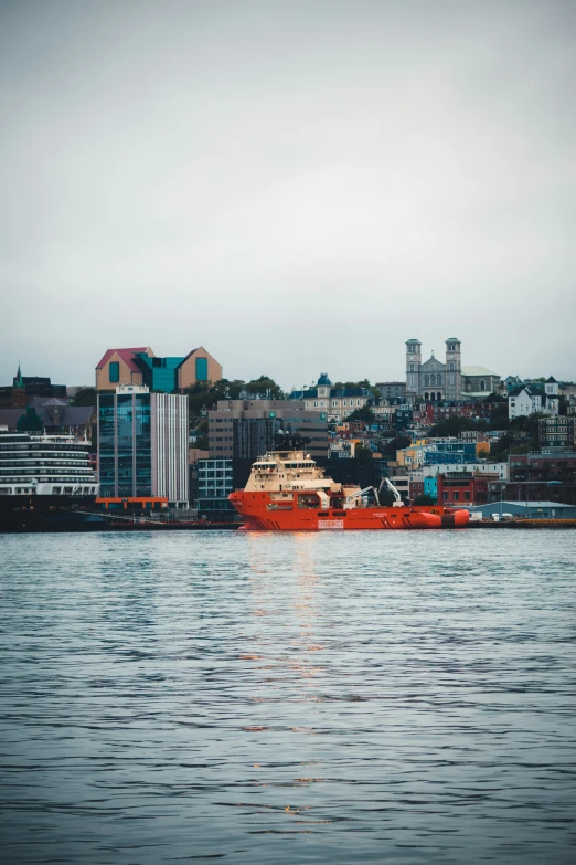 a red boat sitting in a river near the ocean