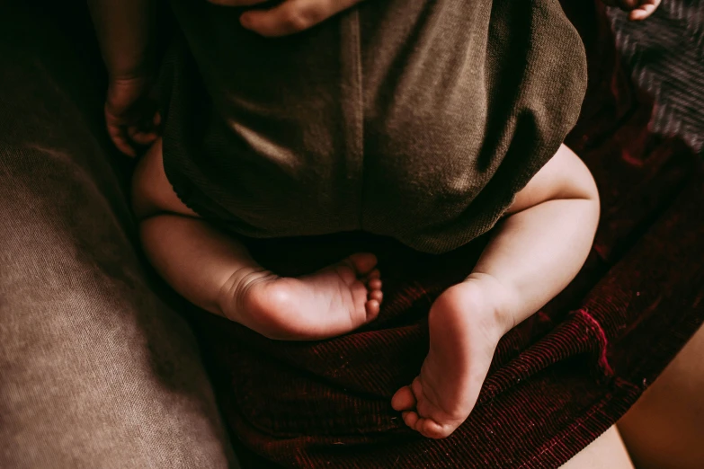 a baby holding onto its moms feet while it sleeps