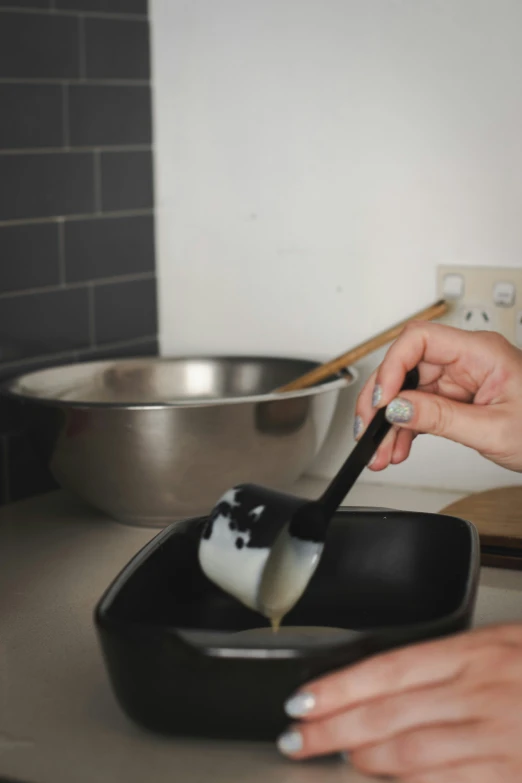 the person is using a spoon to dip cheese in food