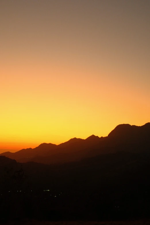 silhouetted mountains and orange sky at dusk