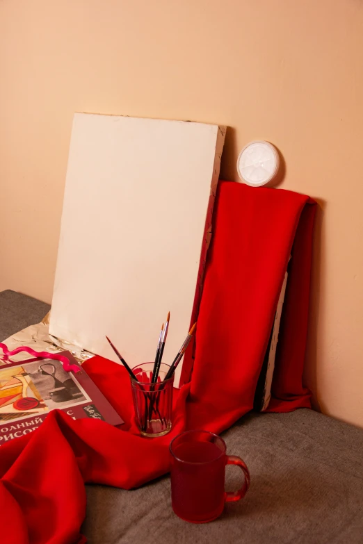 a po of red cloth with pencils and paper