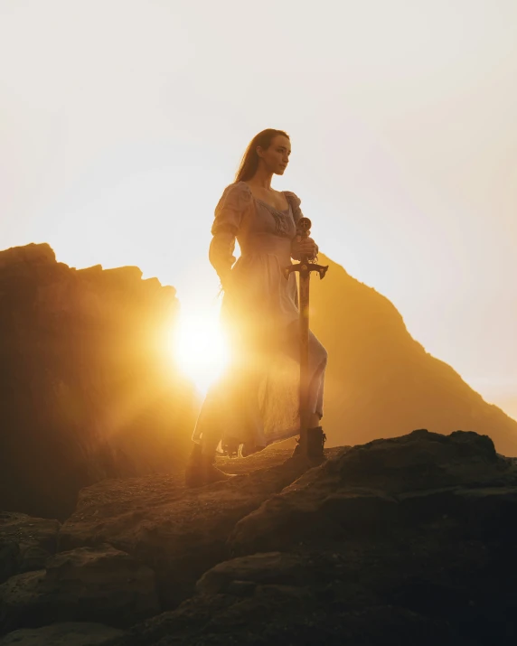 a man standing on a rocky cliff, holding onto a scooter