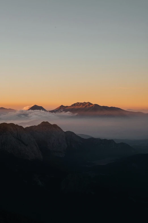 a mountain with clouds and some mountains below it