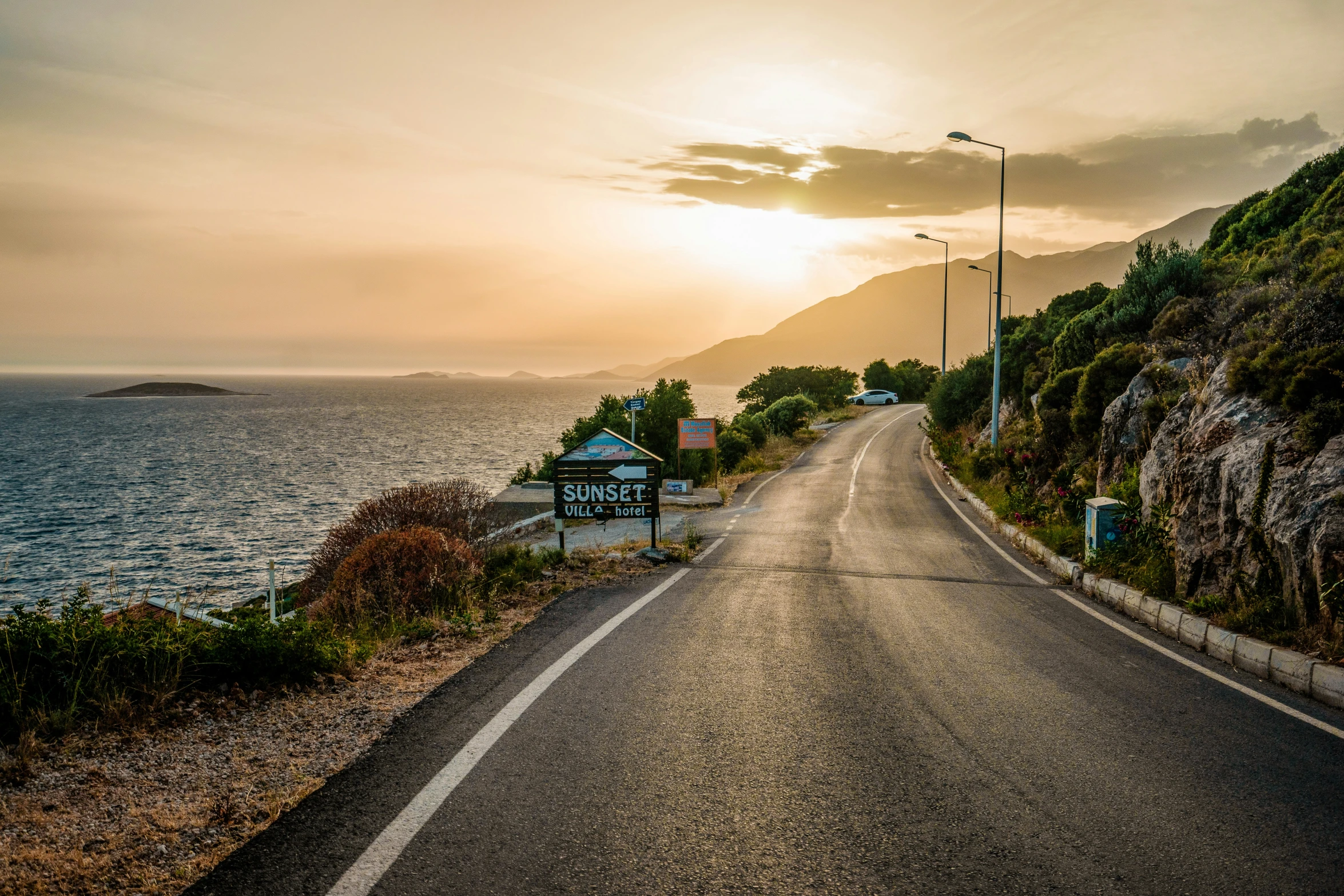 a long empty road next to a lake