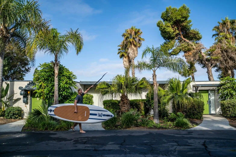 there is a male surfer standing on the street holding his surf board