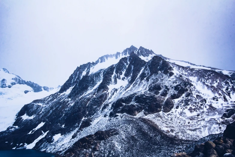 a big snow covered mountain with water in the background