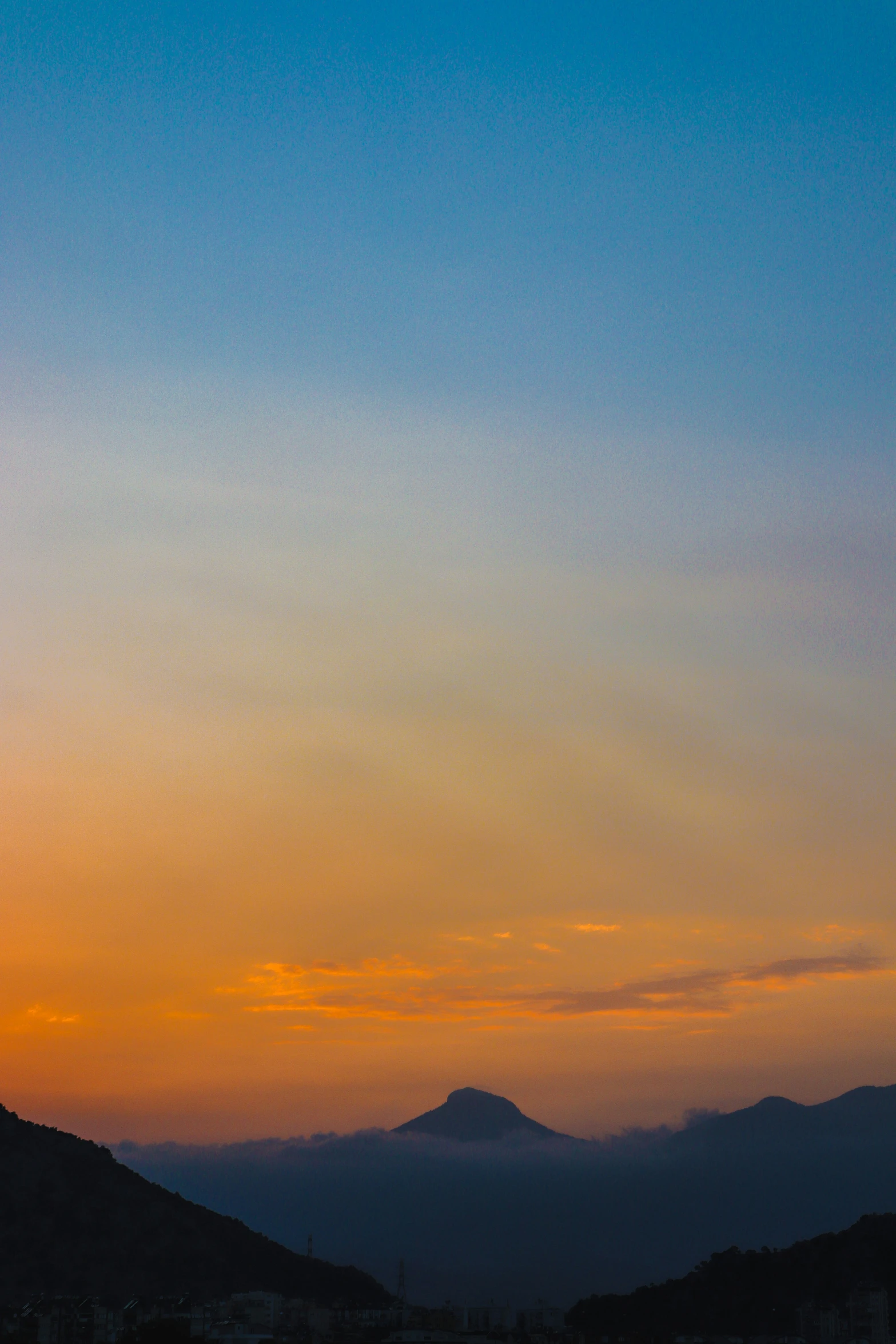 a bird is flying into the sunset with mountains in the background