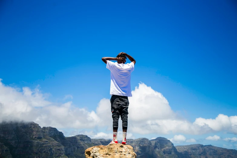 the man is standing on top of a mountain, his head bowed