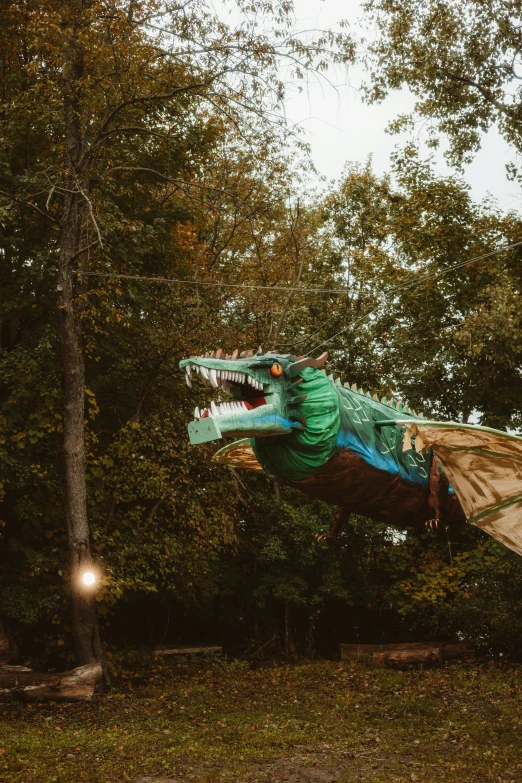 an inflatable dragon flying in the forest with its mouth open