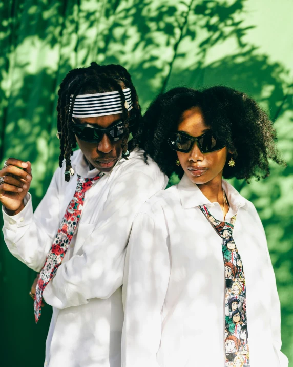 two people wearing ties are standing by some green background