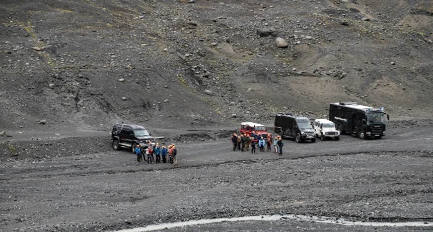 a group of people standing in front of four trucks