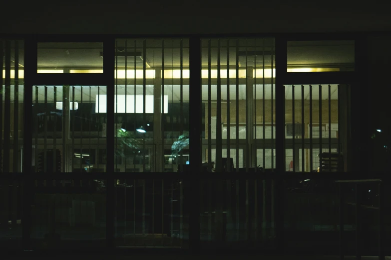 the room is dark and contains a view of an apartment building with lights from outside