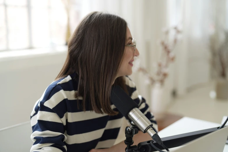 a woman sitting at a table in front of a microphone