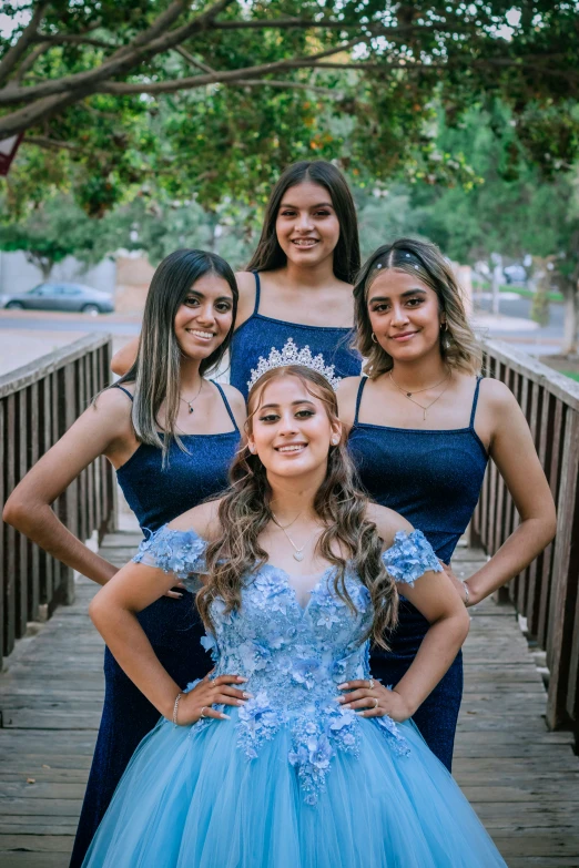 four women dressed in long blue dresses pose for the camera