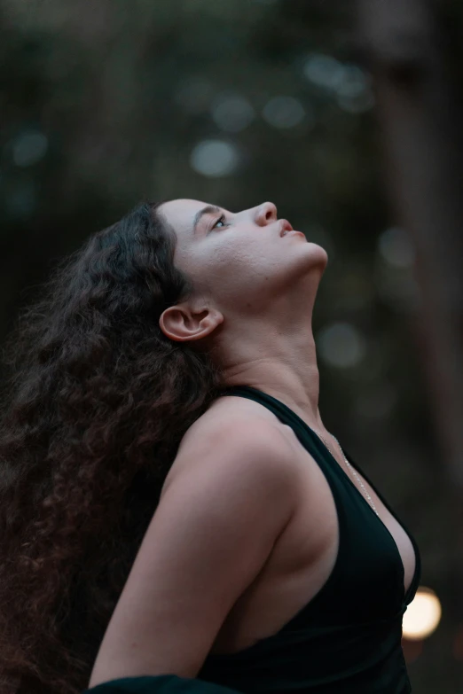 woman in black tank top looking up in the air