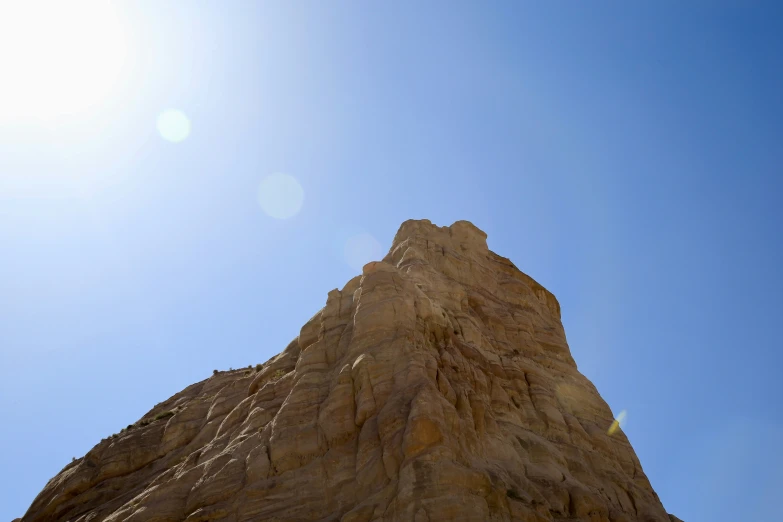 a very tall brown rock in the middle of a clear sky