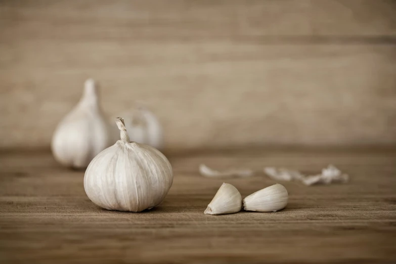 two garlic heads and three garlic cloves on a table