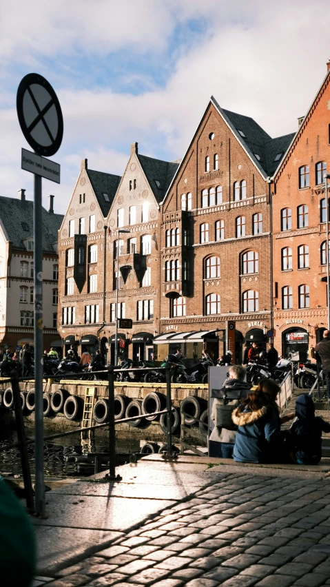 a street sign sitting next to buildings on a cobblestone surface