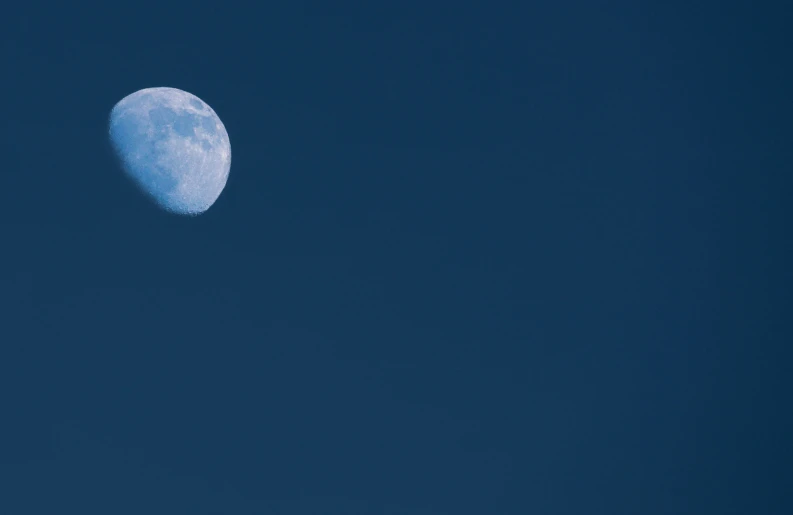 the moon is on the horizon in a blue sky