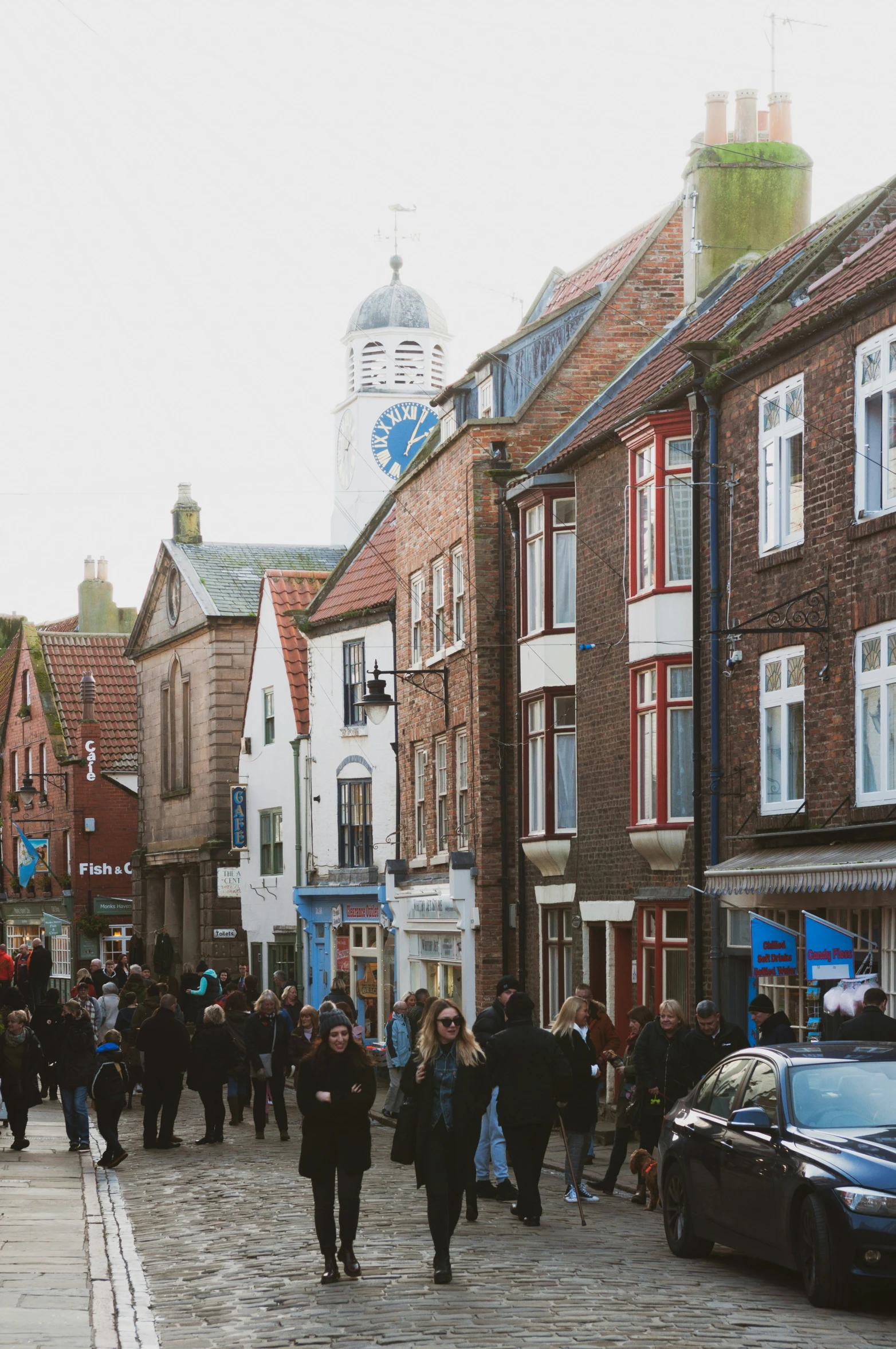 people walking on a cobblestone walkway between some buildings